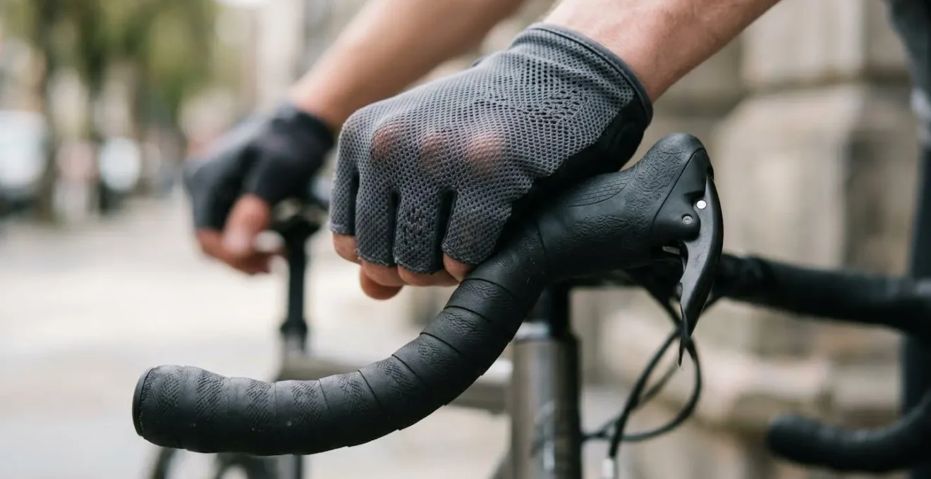 Close-up of hands wearing lightweight cycling gloves gripping shared bike handlebars showing protective barrier method